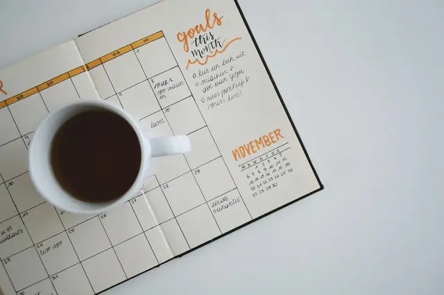 A planning calendar beside a cup of coffee