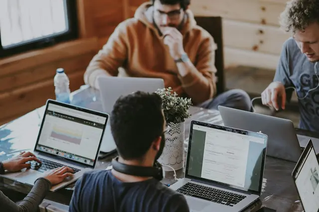 People collaborating with laptops around a table