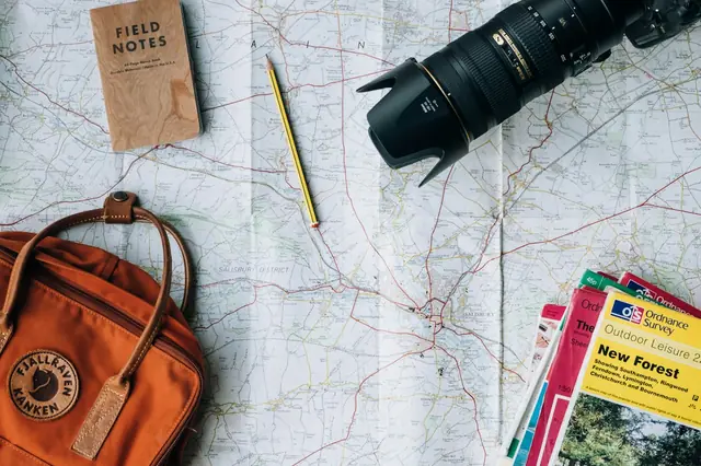 A camera and travel items beside a map on a desk